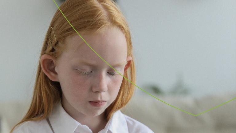 Meisje met lang rood haar, sproetjes en witte blouse kijkt sip naar beneden