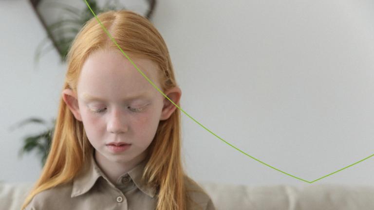 kindje met lang rood haar kijkt naar de grond