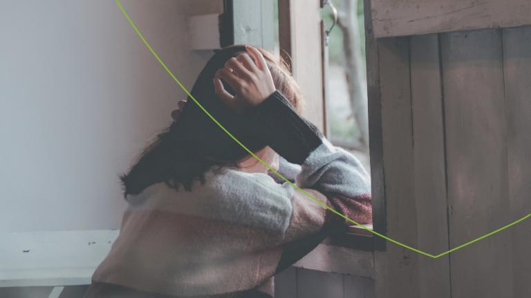 Vrouw met handen in het haar voor het raam